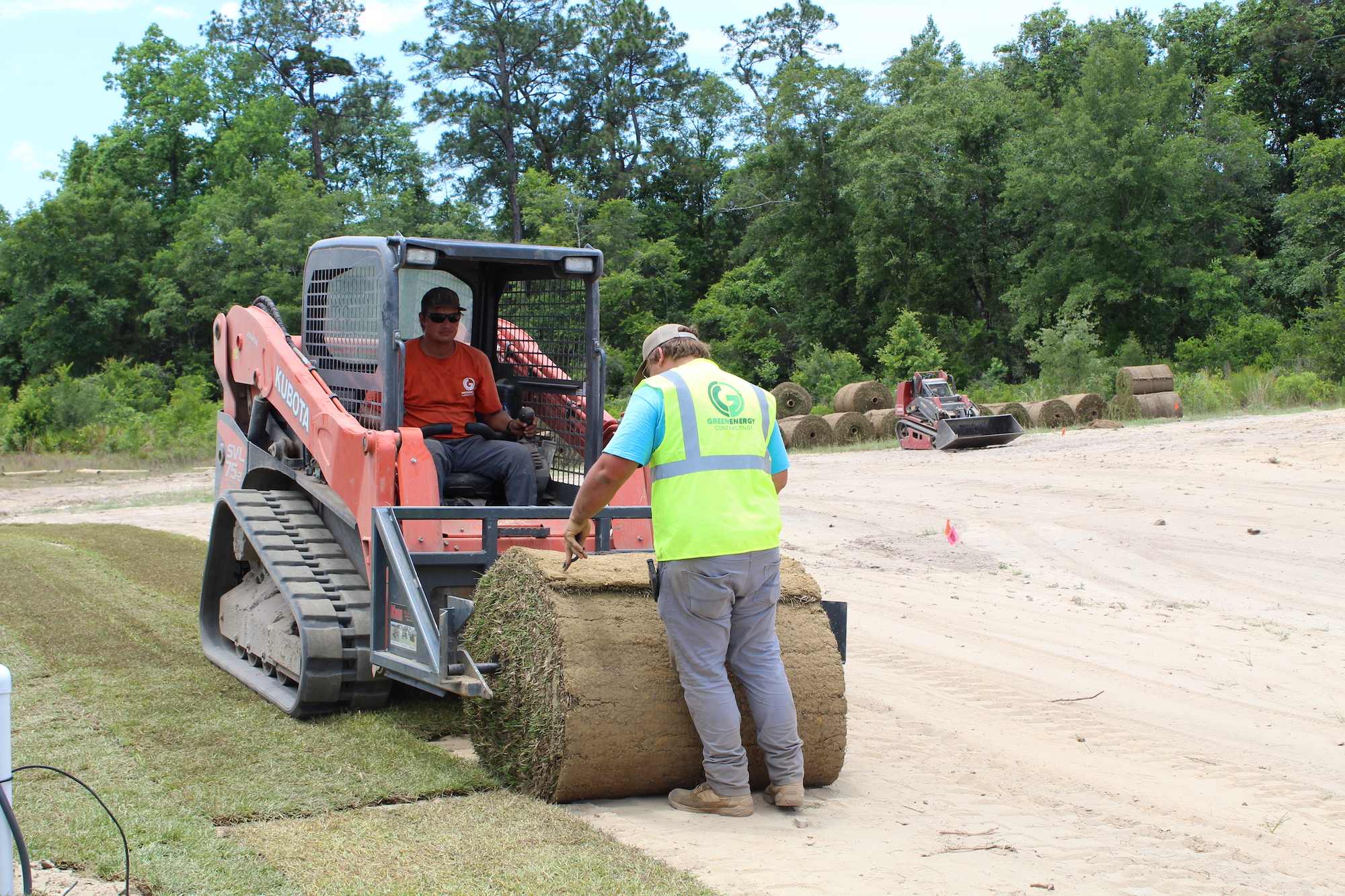 Two GEL employees rolling out sod with a machine